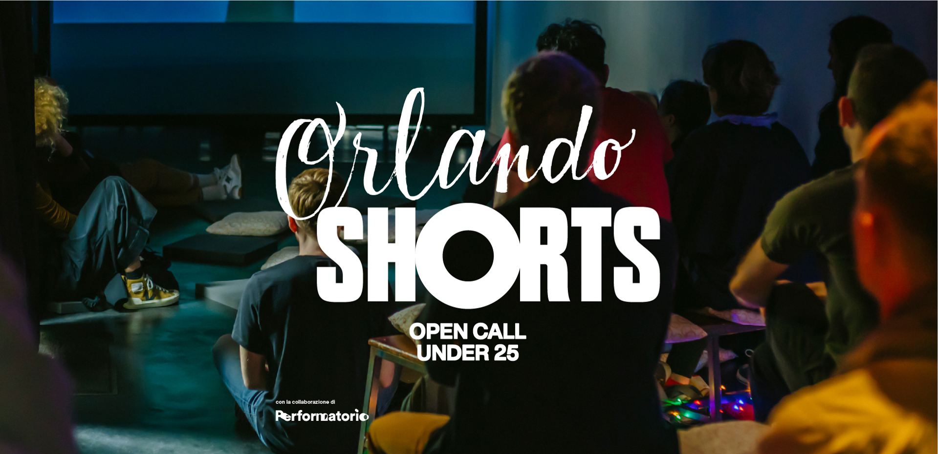 “Persone sedute in una piccola sala buia guardano uno schermo di proiezione, con in sovrimpressione la grafica ‘Orlando Shorts – Open Call Under 25’ e il logo di ‘Reformatorio’ in basso al centro.”