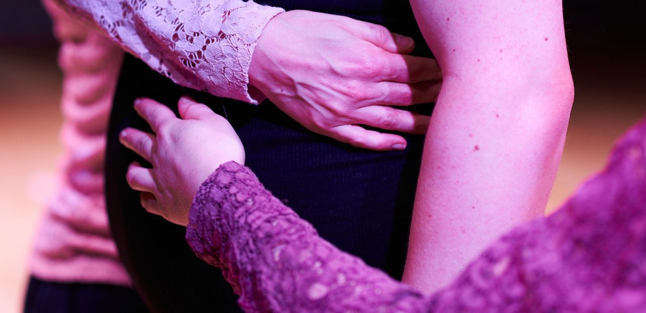 Foto dello spettacolo in cui si vedono un dettaglio di braccia di più persone incrociate su un solo busto.